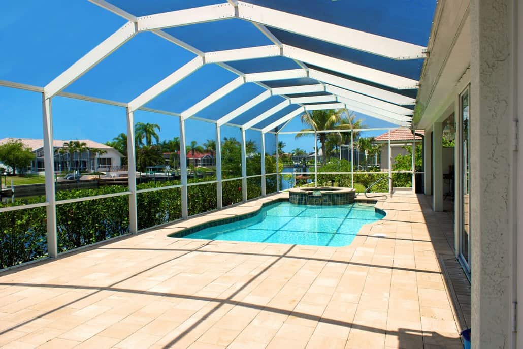 Screened pool deck overlooking a Cape Coral canal lined with waterfront homes and palms